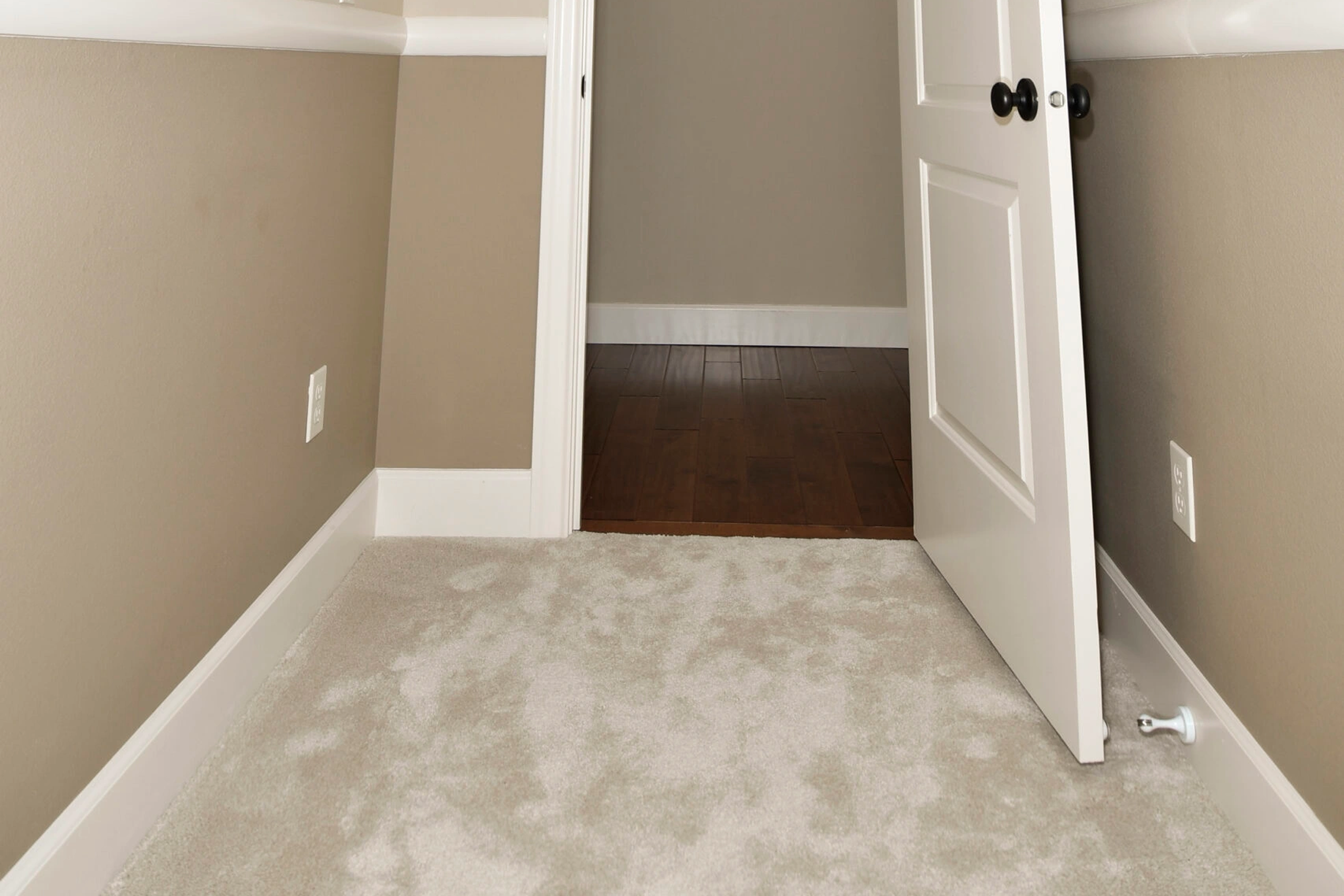 Carpeted hallway with open white door